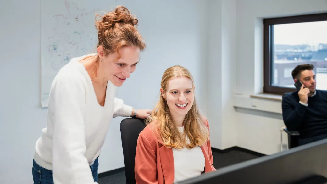 Zwei Frauen sind gemeinsam im Buero und schauen auf einen Bildschirm 