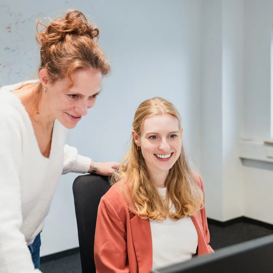 Zwei Frauen sind gemeinsam im Buero und schauen auf einen Bildschirm 